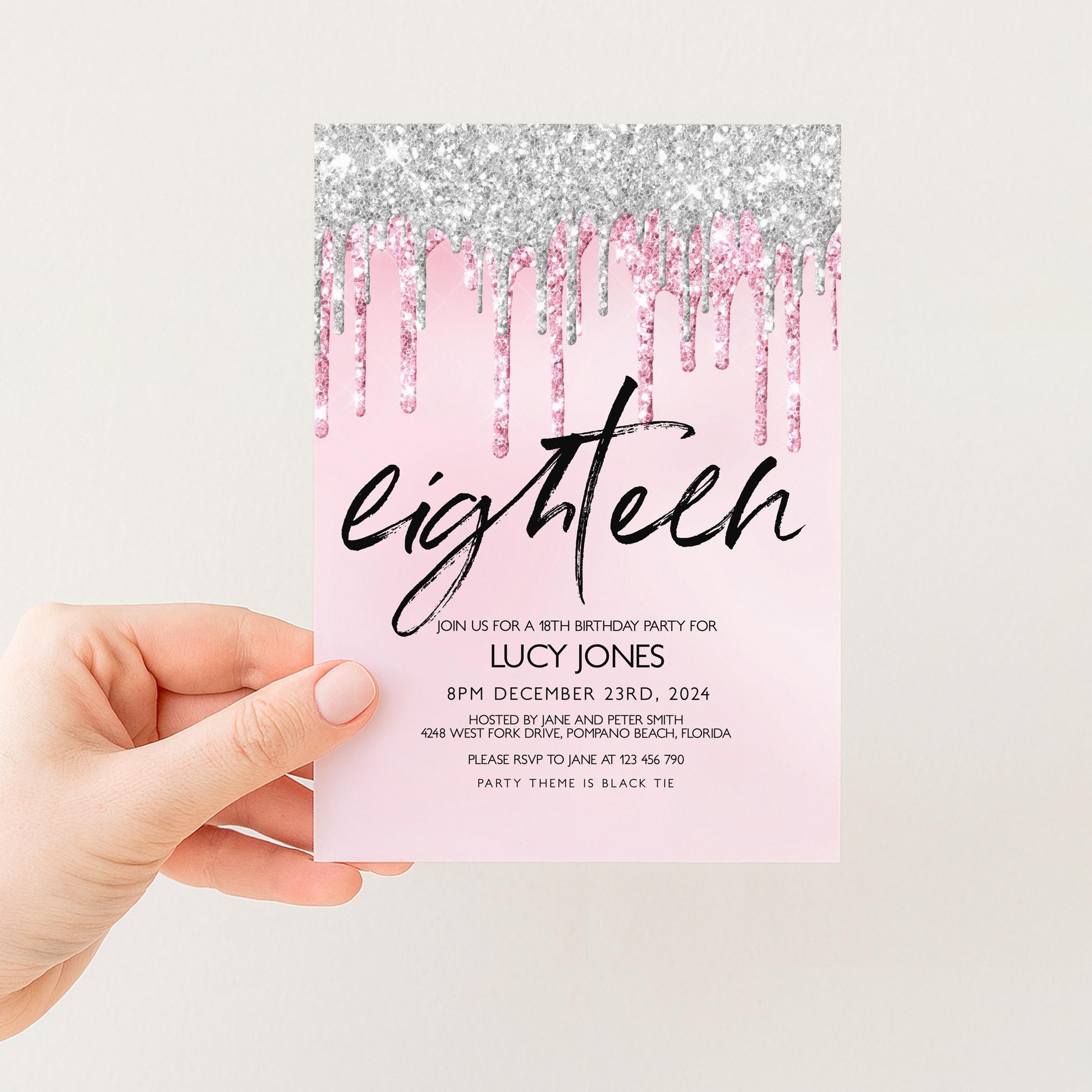 A hand holding a pink invitation card with a glittery design and text.
