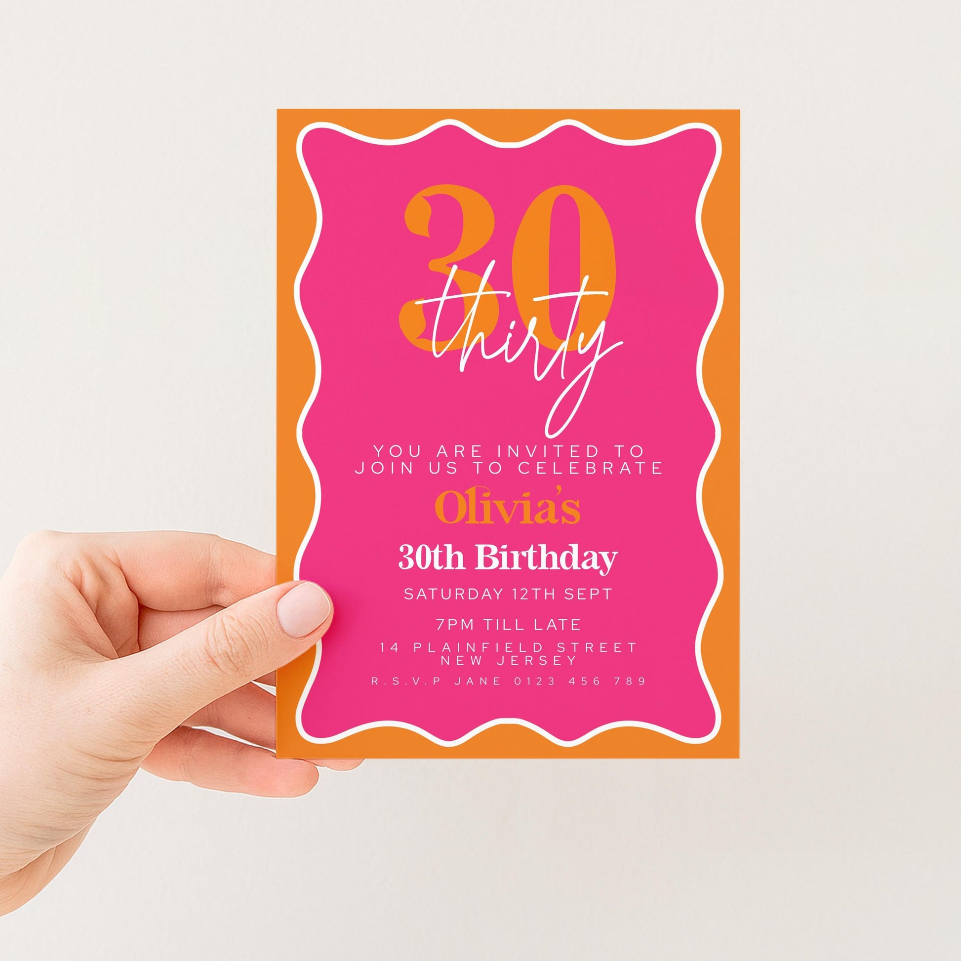 a hand holding a pink and orange birthday invitation card with the text "30th Birthday" and details about the event.