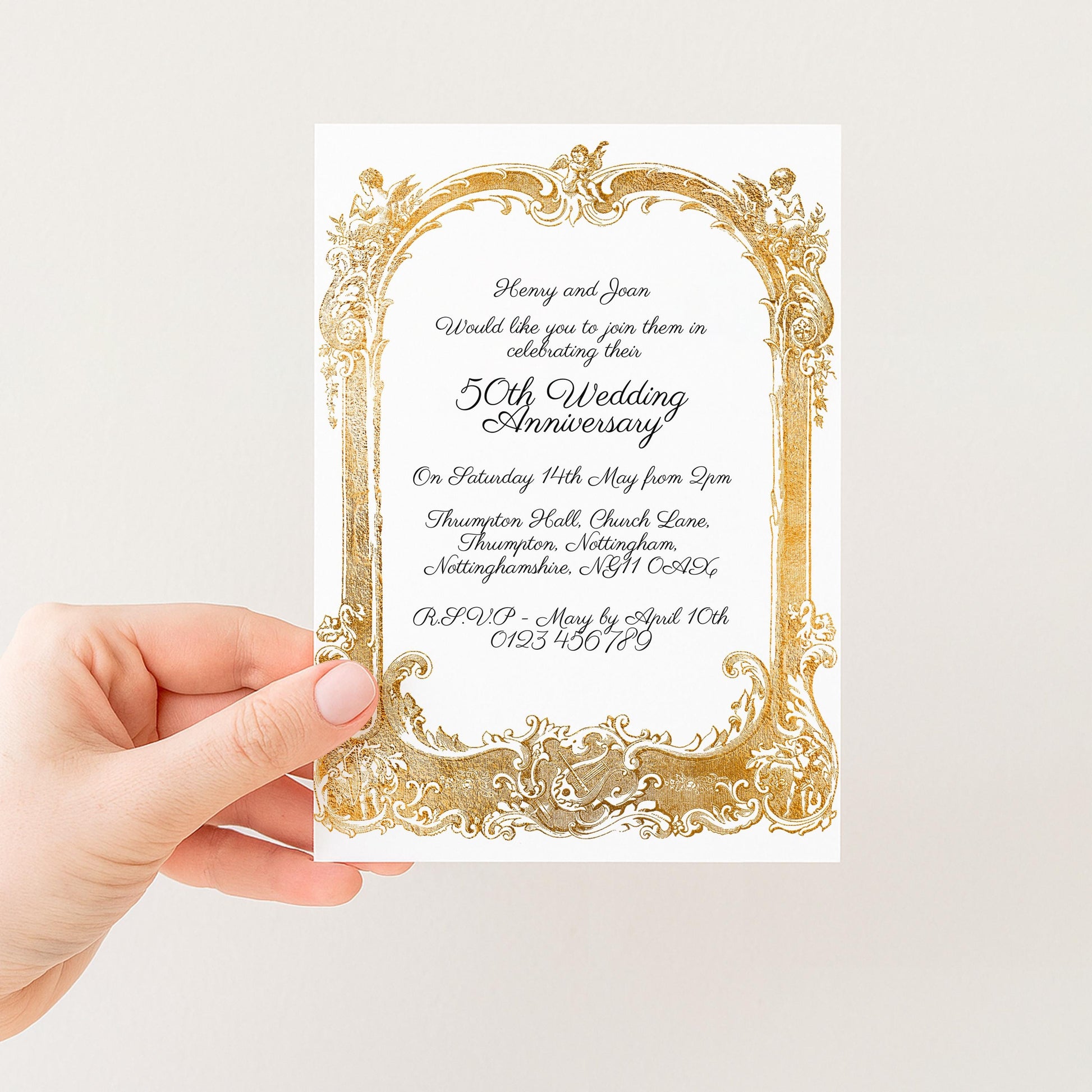 a hand holding a wedding invitation card with an ornate gold frame.