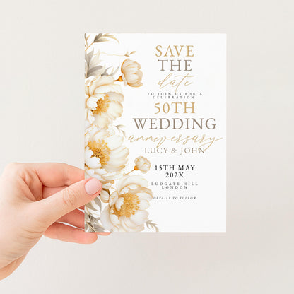 A hand holding a white wedding invitation card with a floral design.