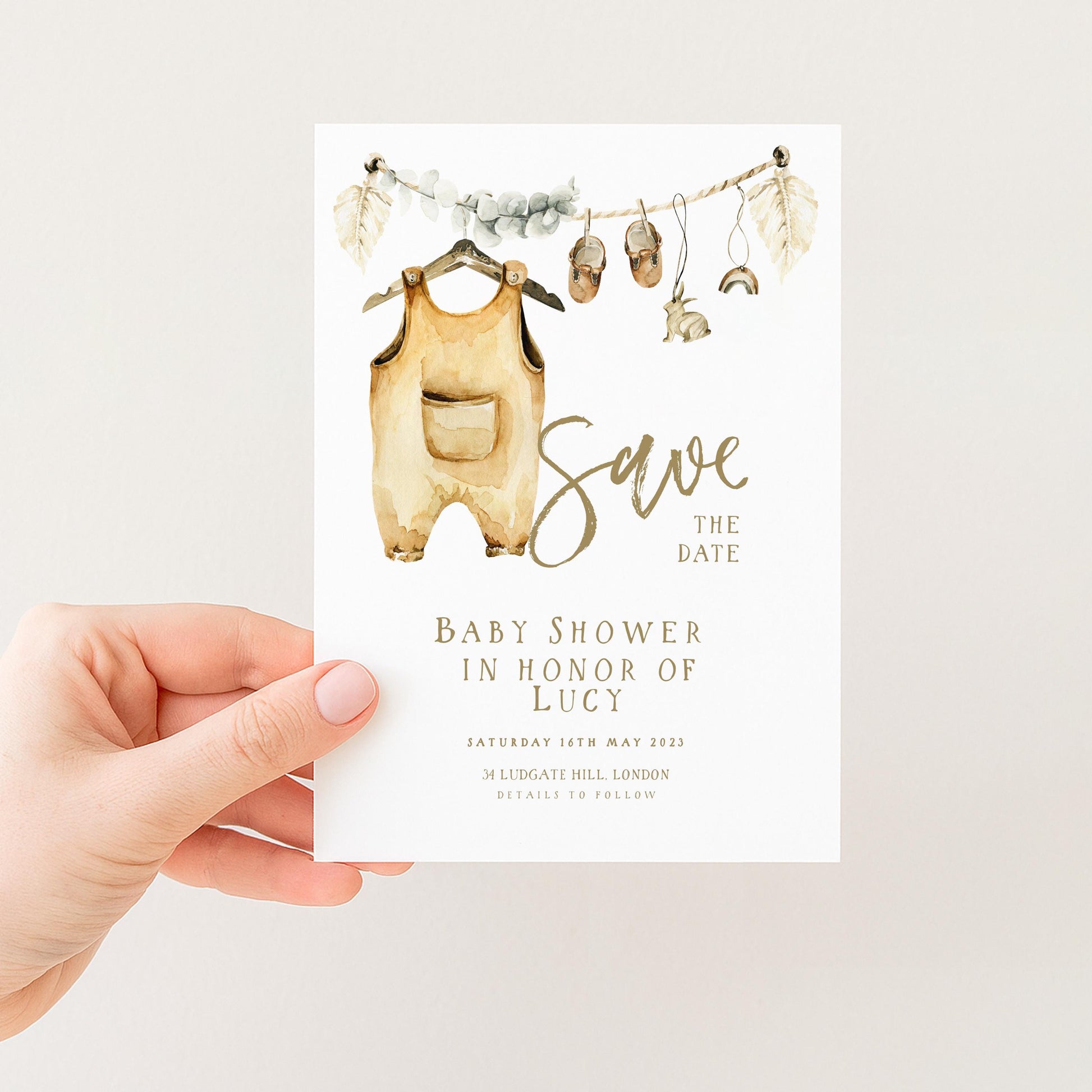A hand holding a white card with a baby shower invitation.