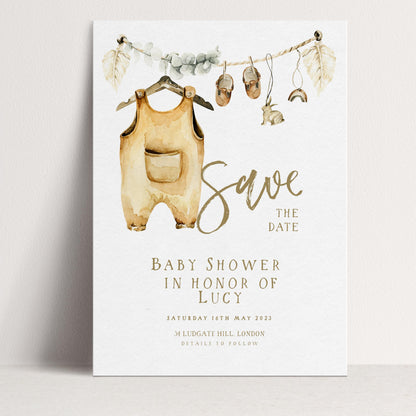 The image is a watercolor print featuring a baby shower invitation with a baby onesie hanging from a clothesline and various baby-related items displayed.