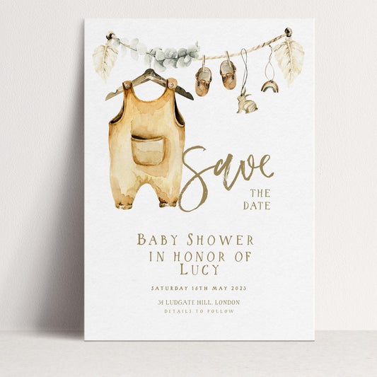 The image is a watercolor print featuring a baby shower invitation with a baby onesie hanging from a clothesline and various baby-related items displayed.