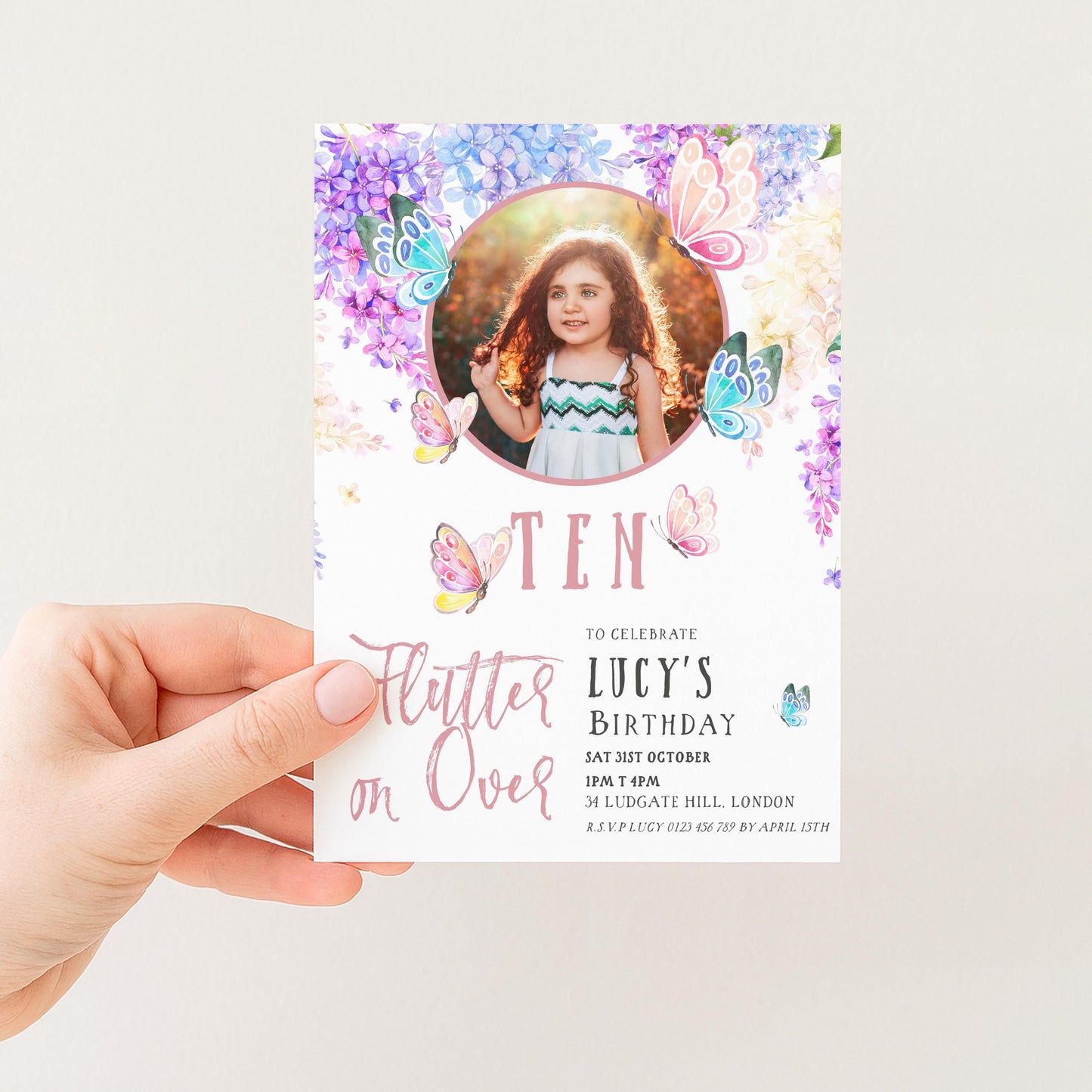 A hand holding a birthday invitation card with a photo of a young girl and butterflies on the cover.
