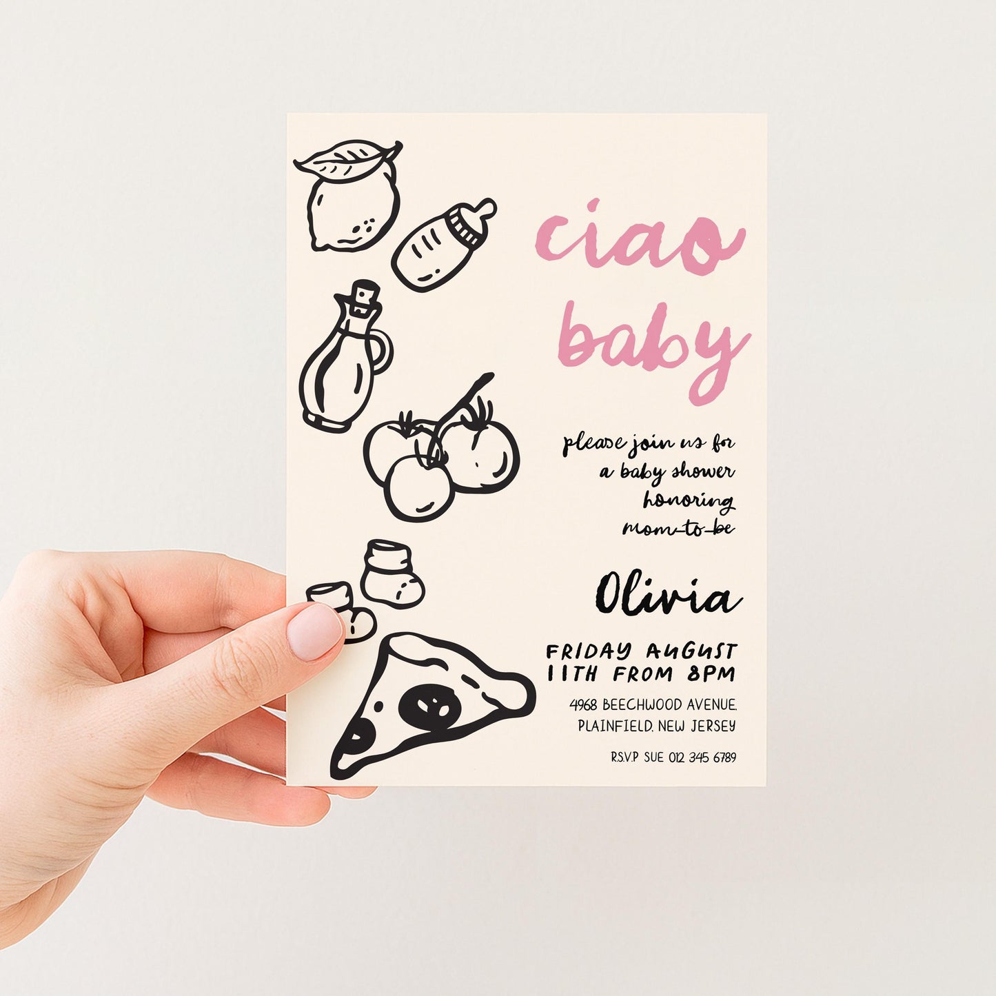 The image is a hand holding a baby shower invitation card with various baby-related illustrations and text.