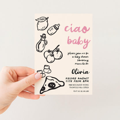 The image is a hand holding a baby shower invitation card with various baby-related illustrations and text.