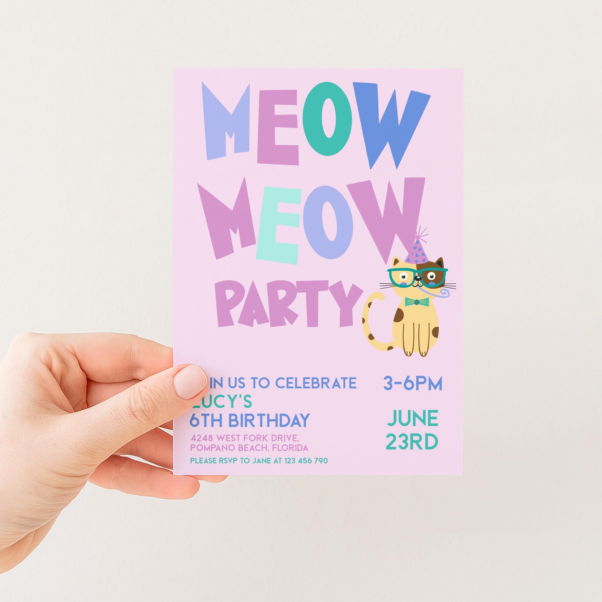 a person holding a pink birthday party invitation with a cat theme.