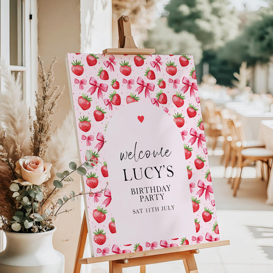 Editable pink strawberry birthday party welcome sign displayed on easel, with watercolor strawberries and bows, personalized for a child's party