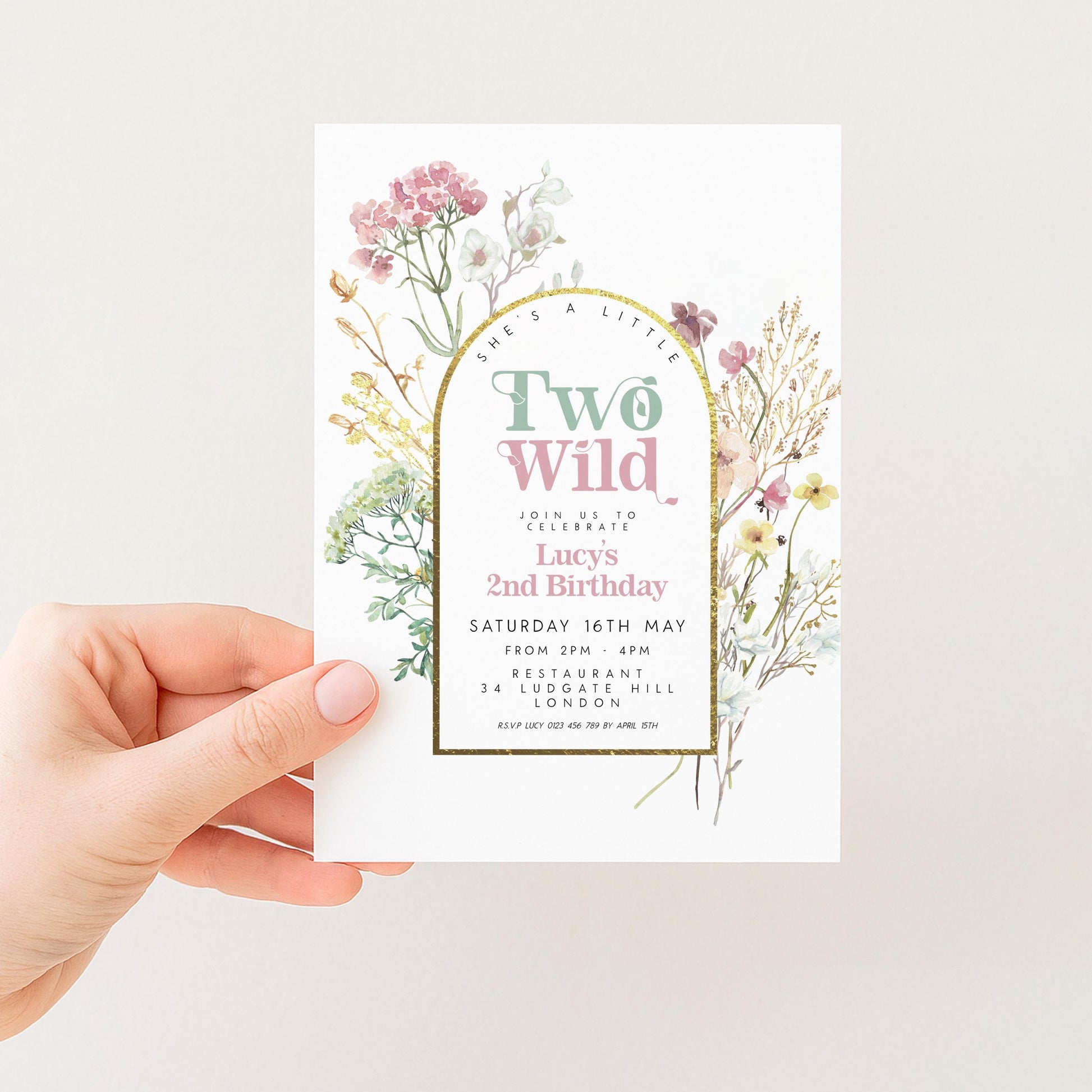 a person holding a white invitation card with a floral design and text.