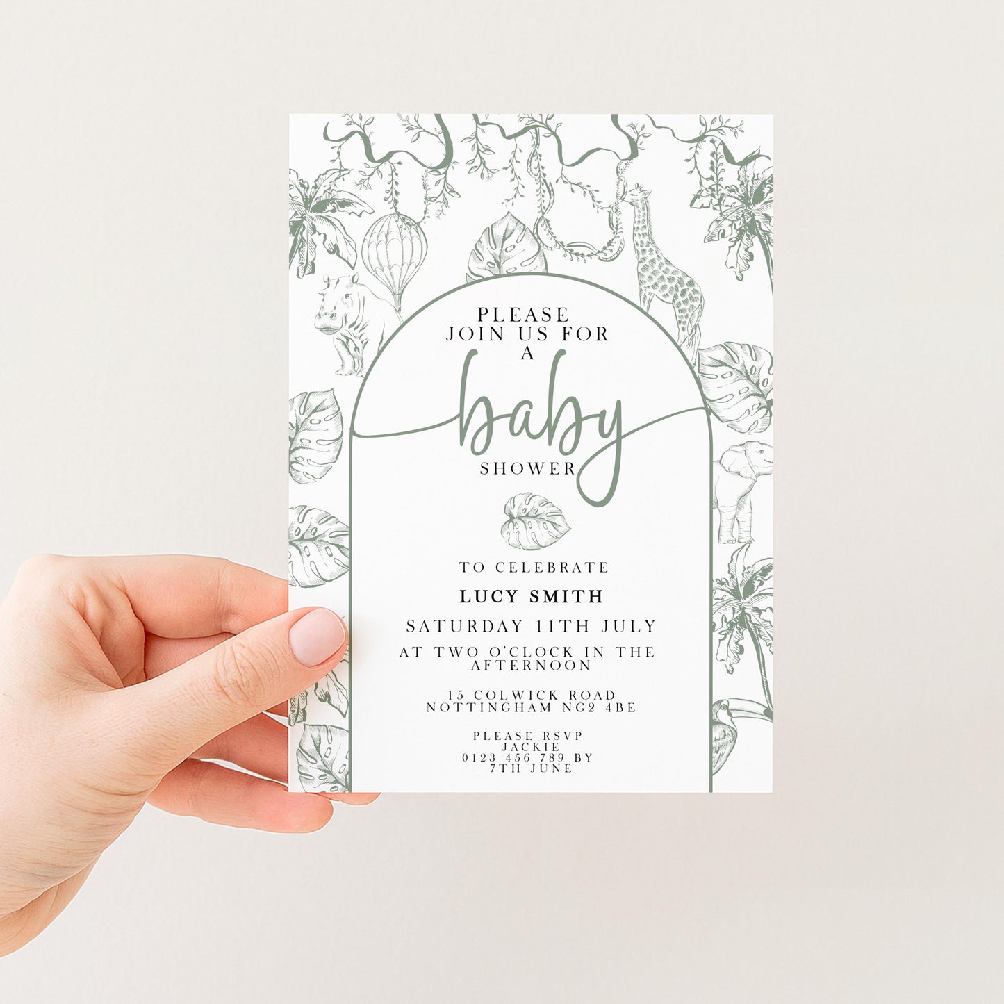 A hand holding a baby shower invitation with a floral design and text.
