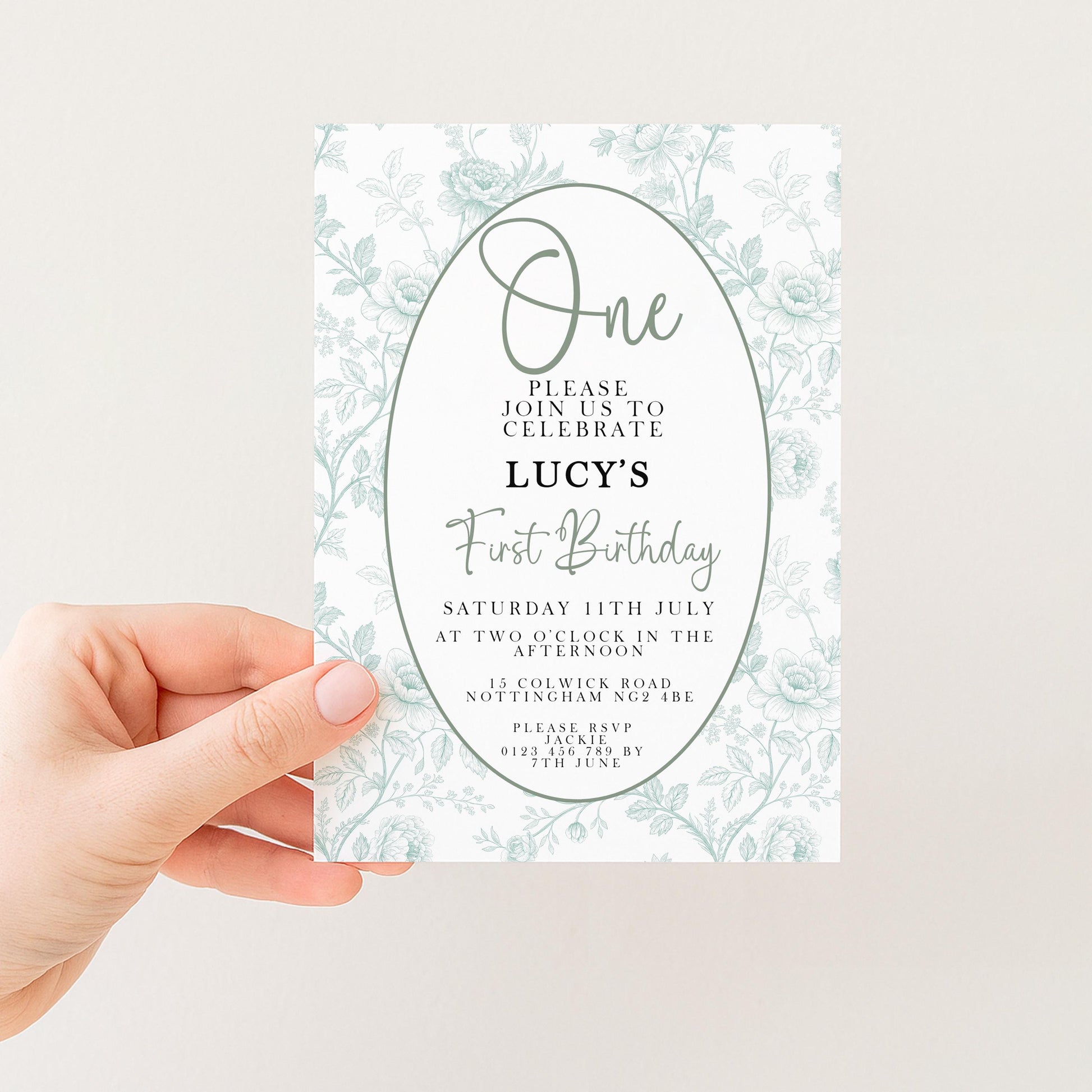 a person holding a white invitation card with a floral design. The card is for a first birthday celebration and invites guests to join in the festivities.