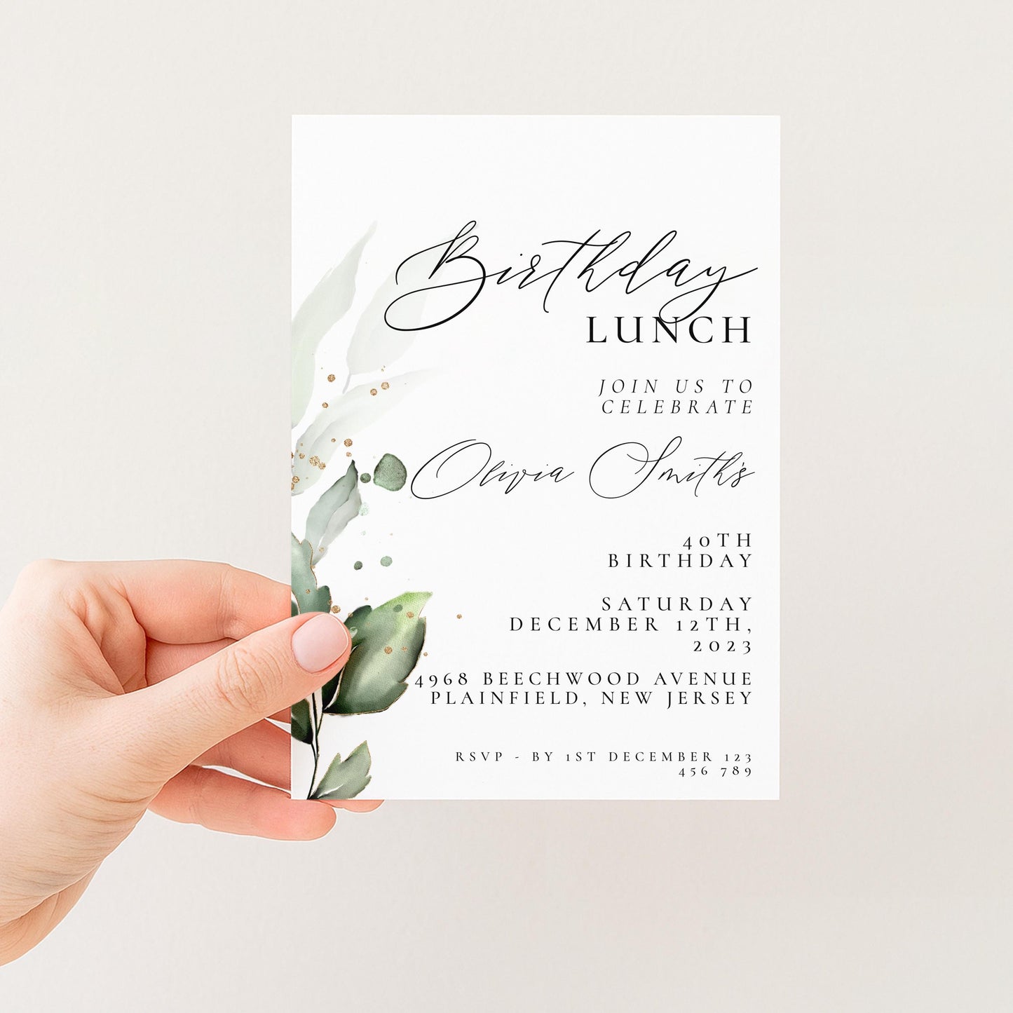 A hand holding a white invitation card with a green leaf design and text.