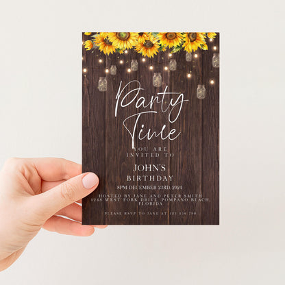 A hand holding a party invitation card with a rustic wooden background and yellow sunflowers.