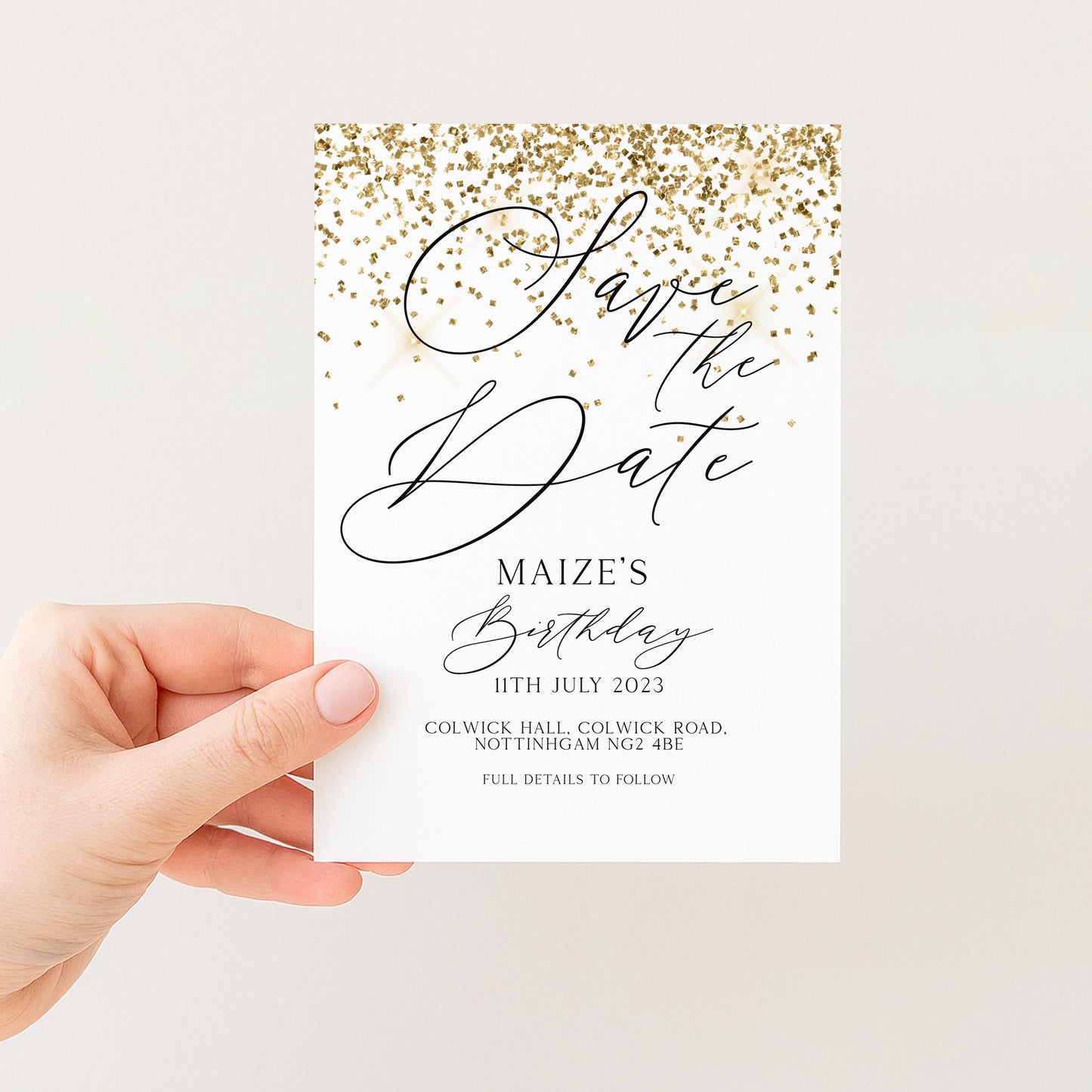 A person's hand holding a white card with gold glitter and text.