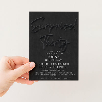 a person holding a black invitation card with text on it.