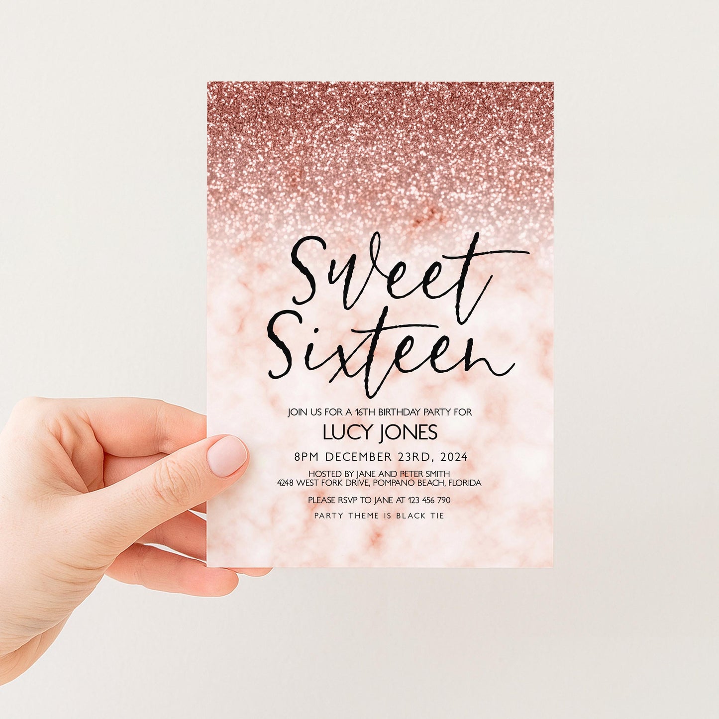 a hand holding a pink and gold glittery invitation card for a 16th birthday party.
