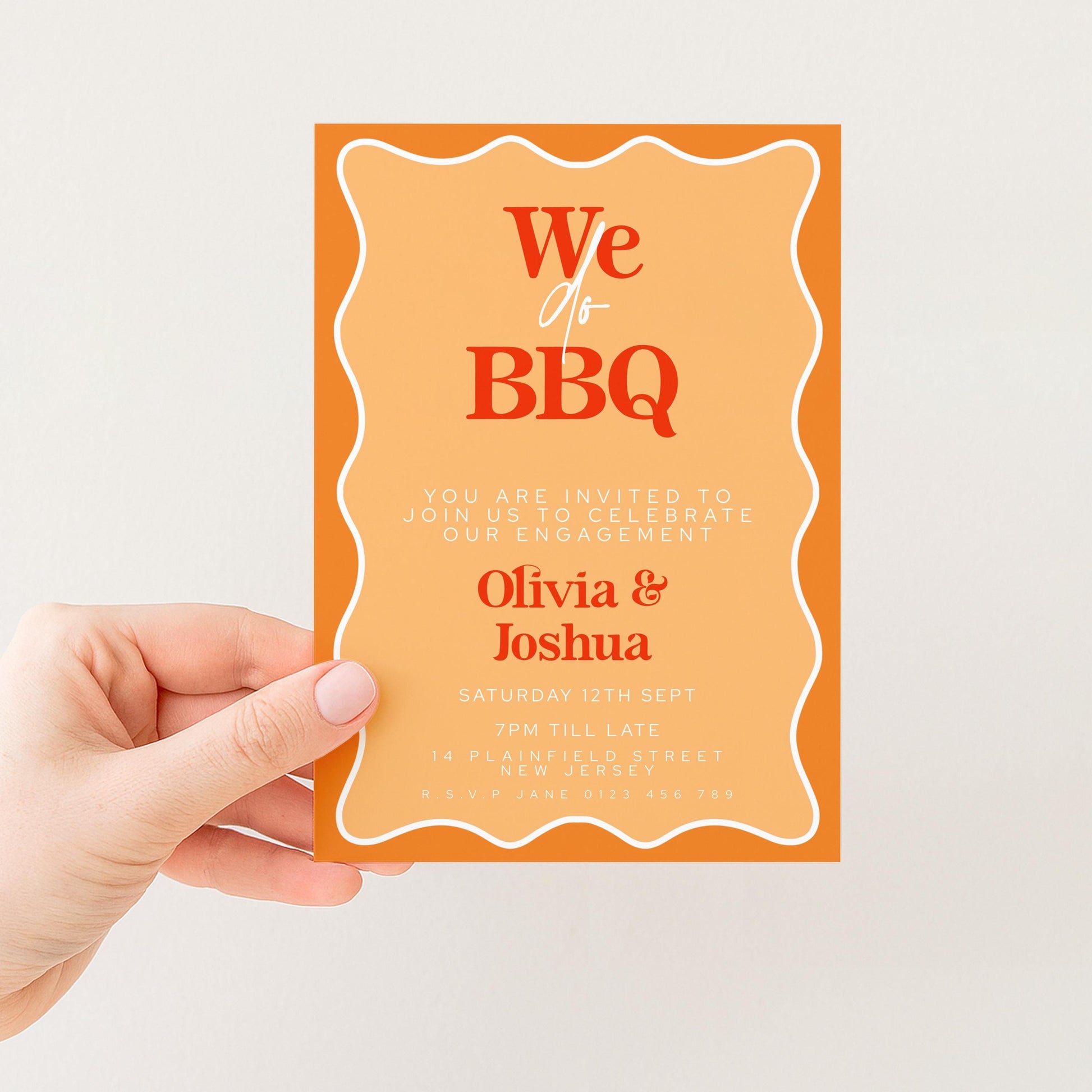 a hand holding a printed invitation card with an orange background and white text.