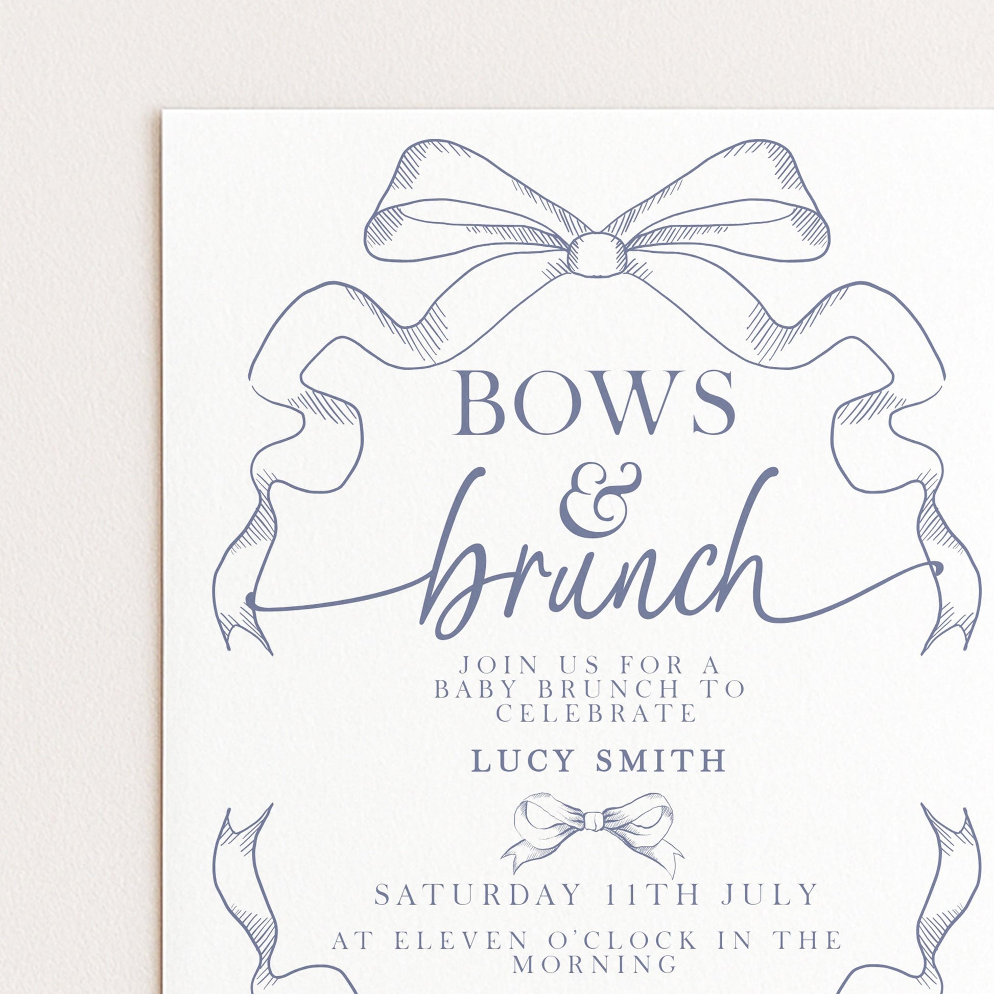 The image is a printed invitation card for a baby shower, featuring a decorative bow and elegant text.