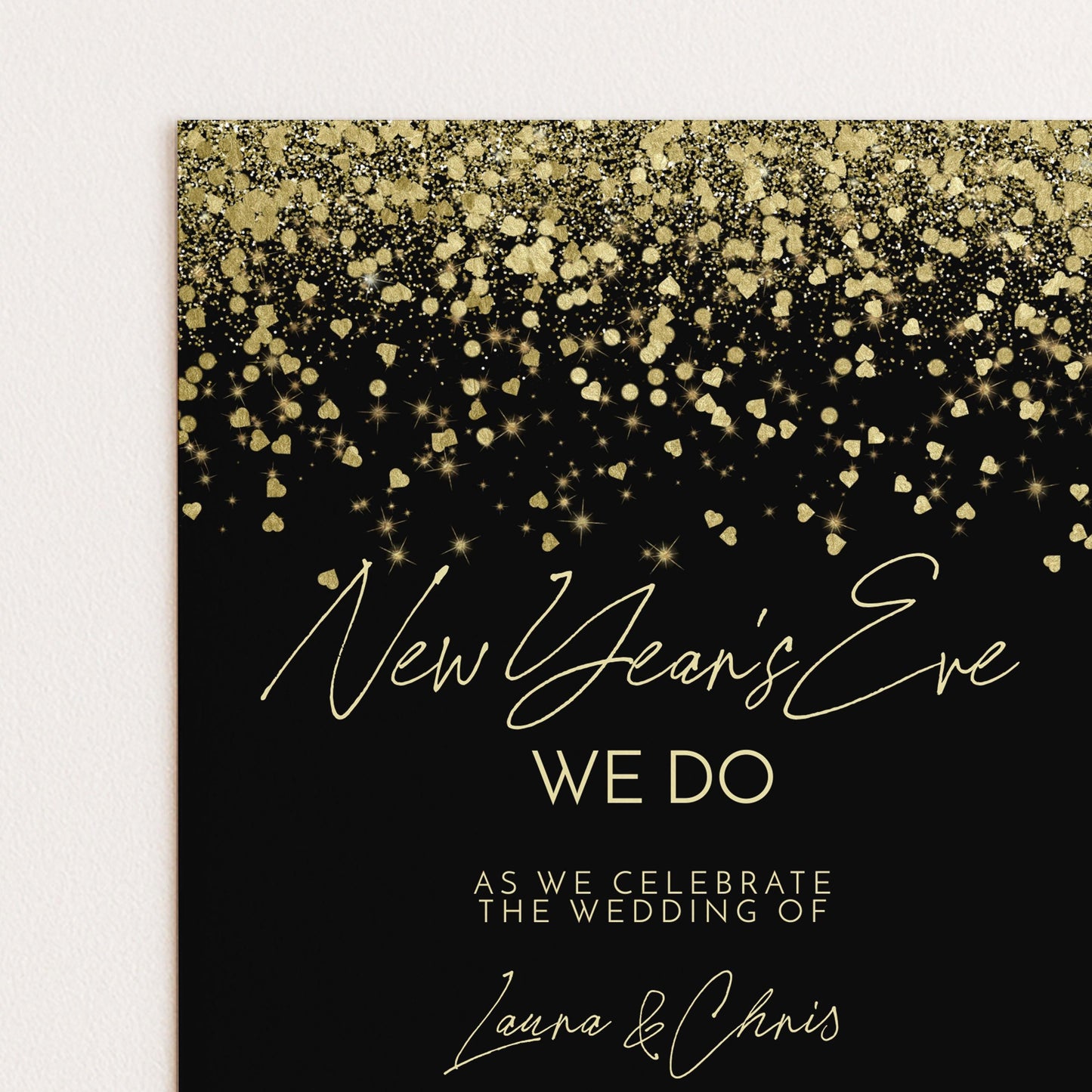 The image is a wedding invitation card with a black background and gold glitter. The text on the card reads "New Year's Eve We Do" and "As we celebrate the wedding of Laura & Chris".
