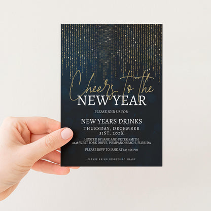 A hand holding a black invitation card with a gold glitter design and text.