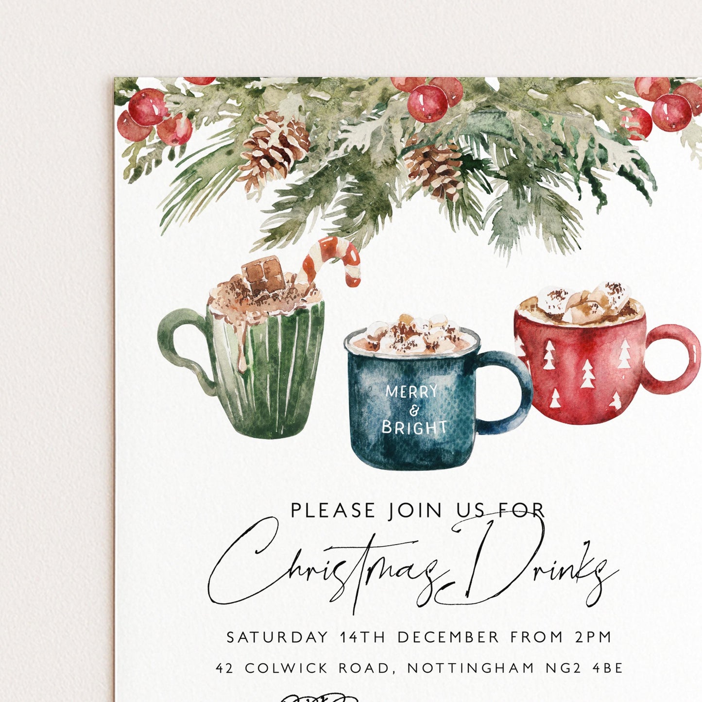 The image is a Christmas-themed invitation card featuring three mugs of hot chocolate with marshmallows, surrounded by a festive wreath and pine cones.