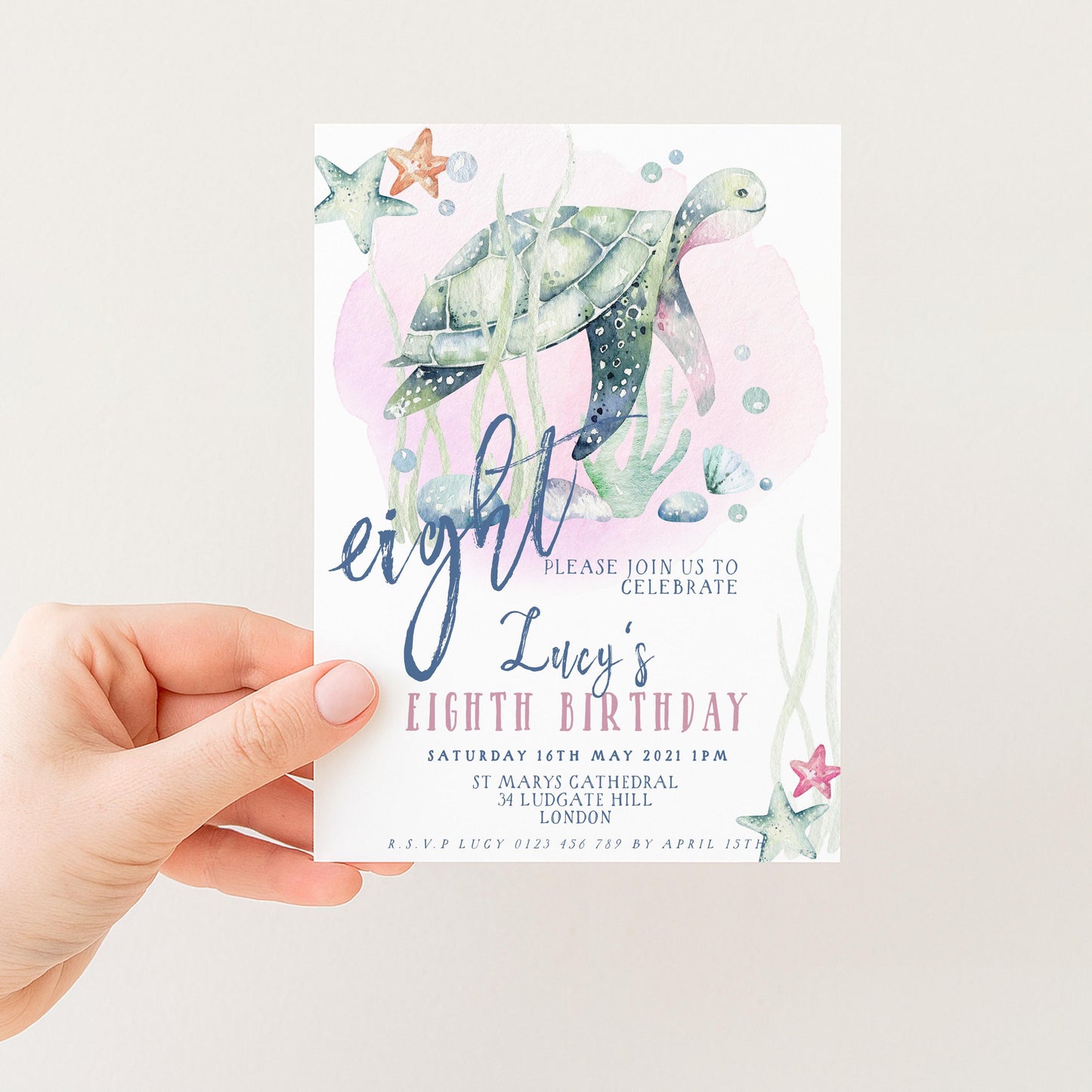 A hand holding a birthday invitation card with a turtle and starfish design, along with text inviting guests to a birthday celebration.