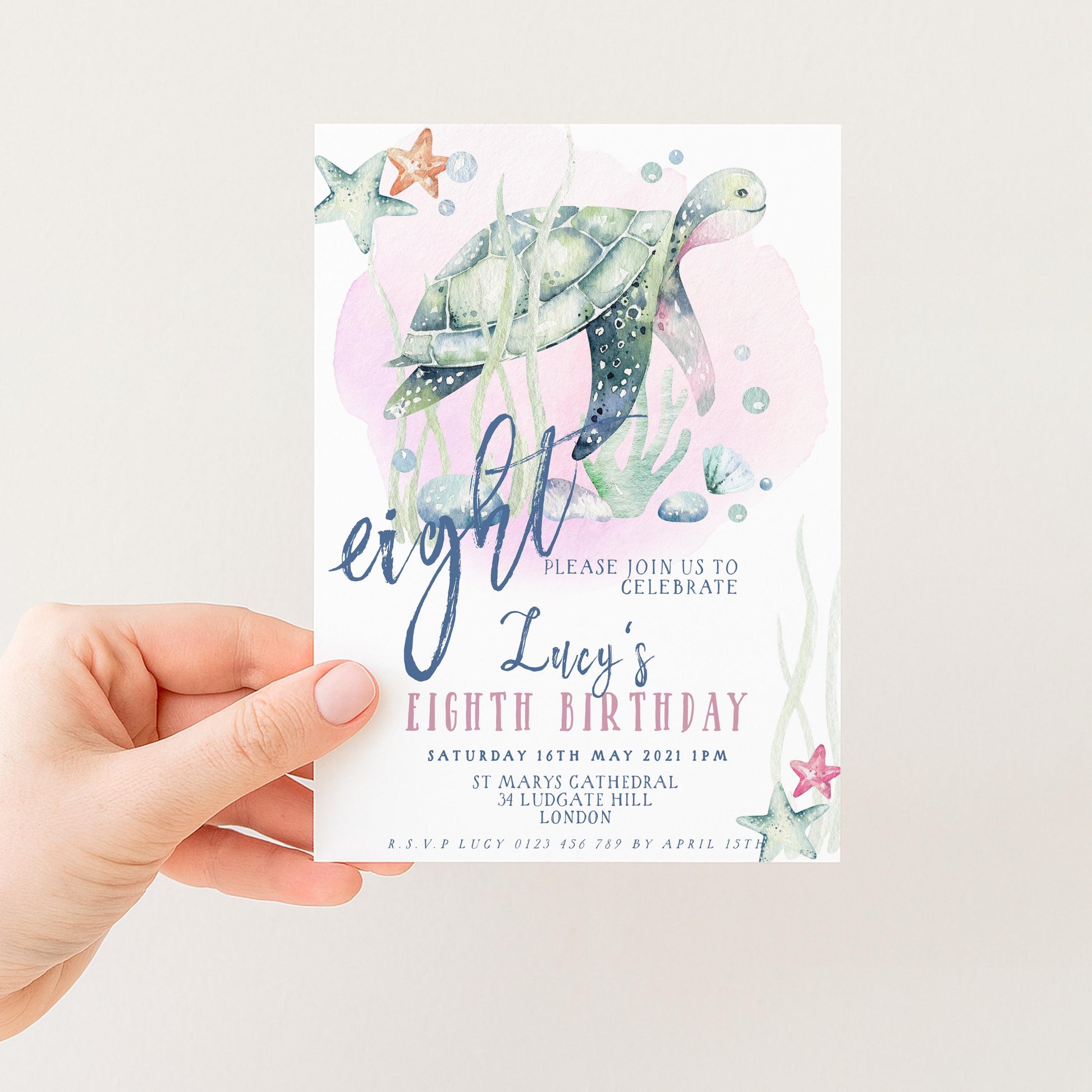A hand holding a birthday invitation card with a turtle and starfish design, along with text inviting guests to a birthday celebration.