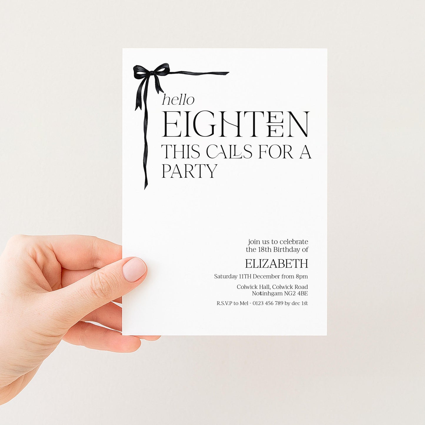 a person's hand holding a white invitation card with black text and a bow.