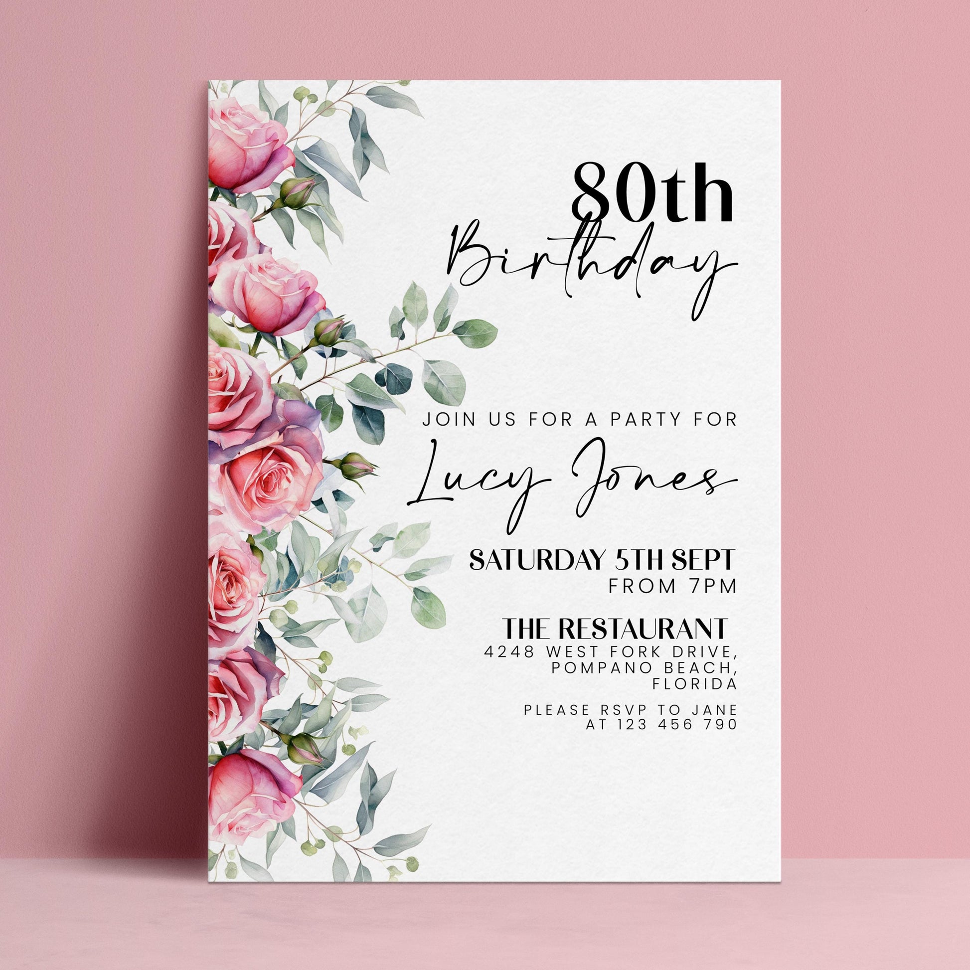 The image is a birthday invitation for a woman named Lucy Jones celebrating her 80th birthday. The invitation is set against a pink background and features a floral design with pink roses and greenery.