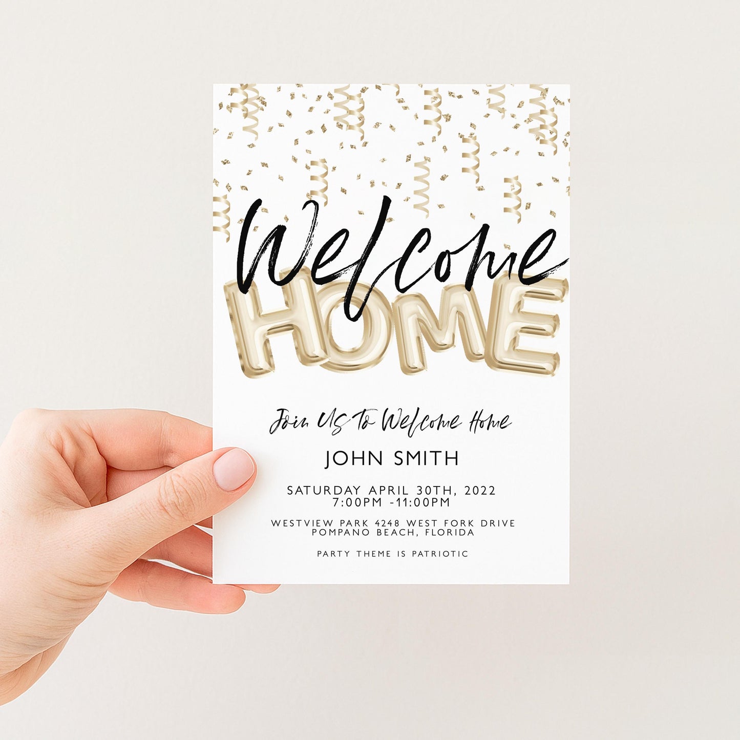 a person holding a white invitation card with gold text and confetti-like designs.