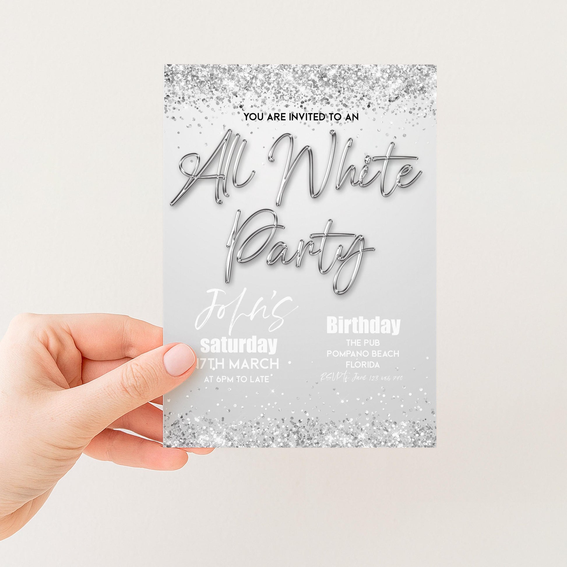 a hand holding a party invitation card with a silver glitter design.
