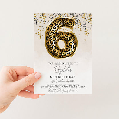 a person holding a birthday invitation card with a leopard print design and gold confetti.