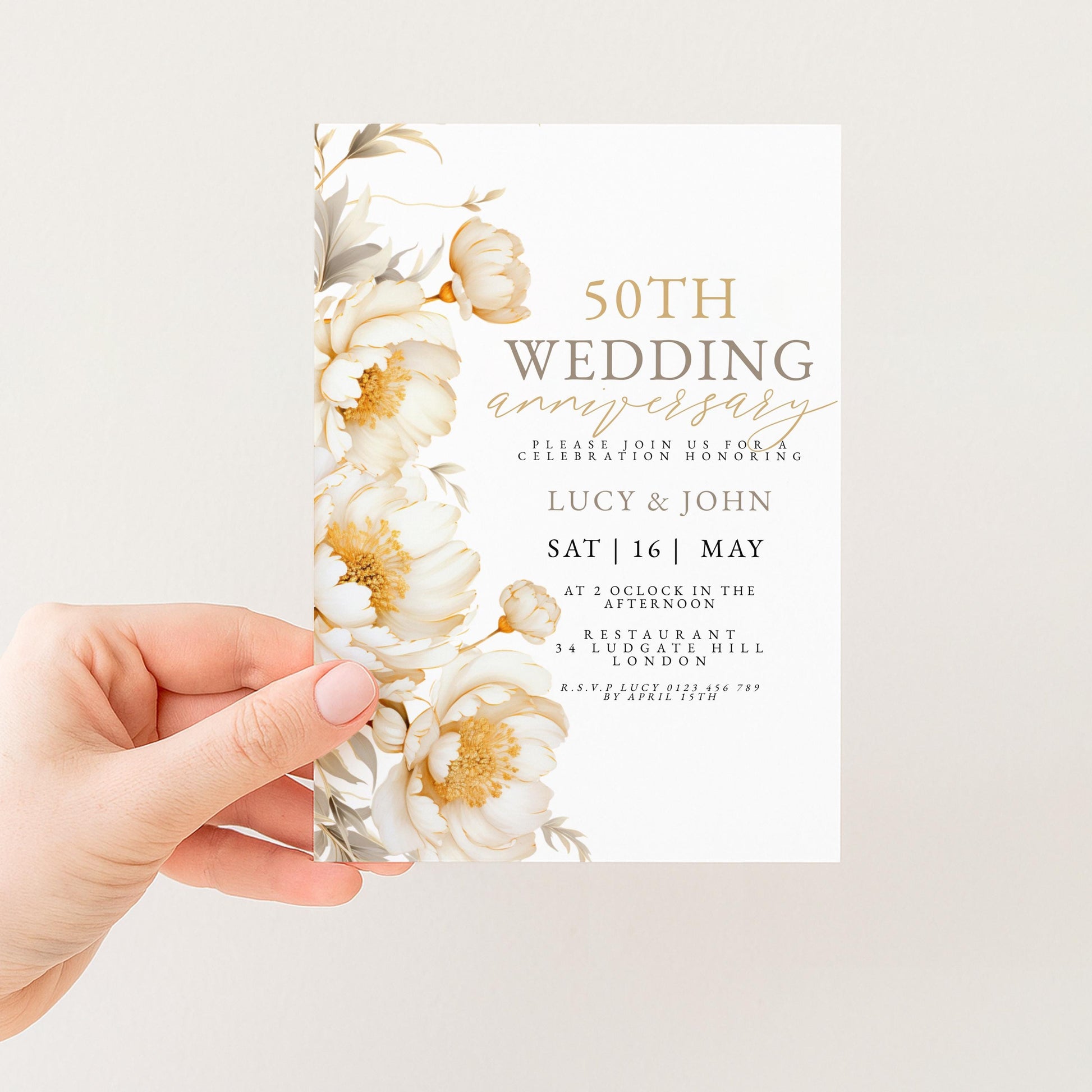 a hand holding a wedding invitation card with a floral design.