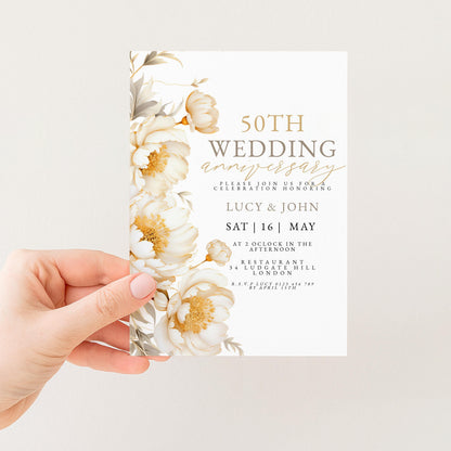 a hand holding a wedding invitation card with a floral design.