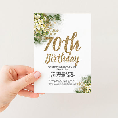 A hand holding a white invitation card with a floral design and text.