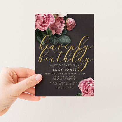 a hand holding a birthday invitation card with a floral design and gold text.