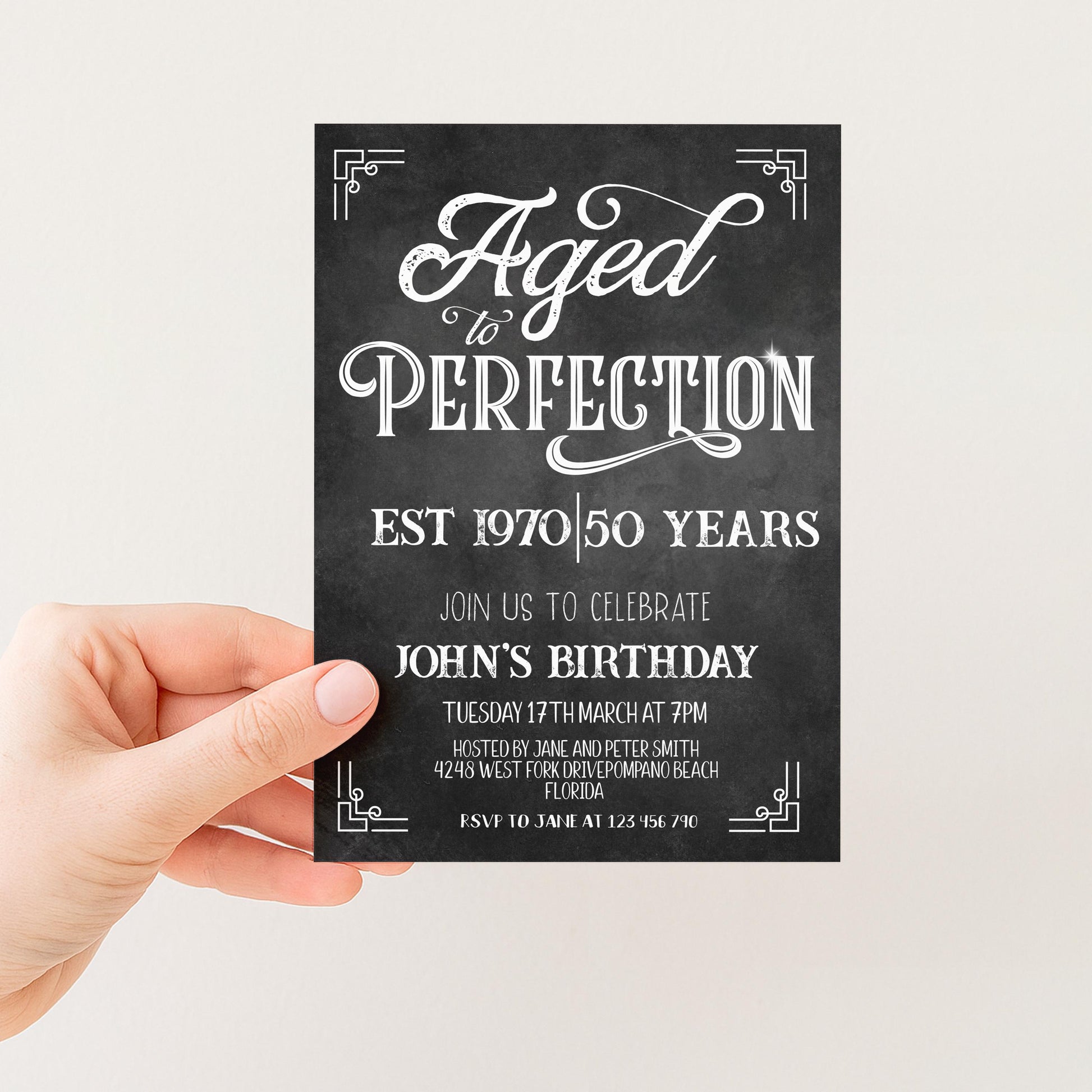 a hand holding a black and white invitation card with text and decorative elements.