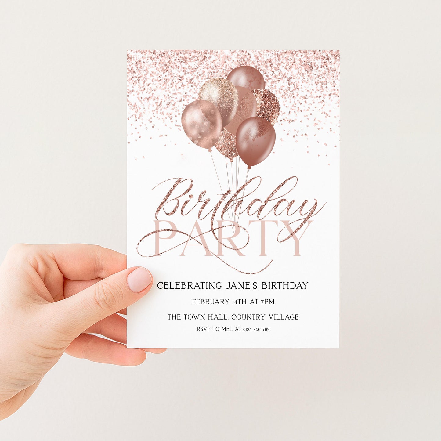 a hand holding a birthday party invitation card with a pink and gold color scheme. The card features a design of pink and gold balloons floating above the text "Birthday Party" and "Celebrating Jane's Birthday".