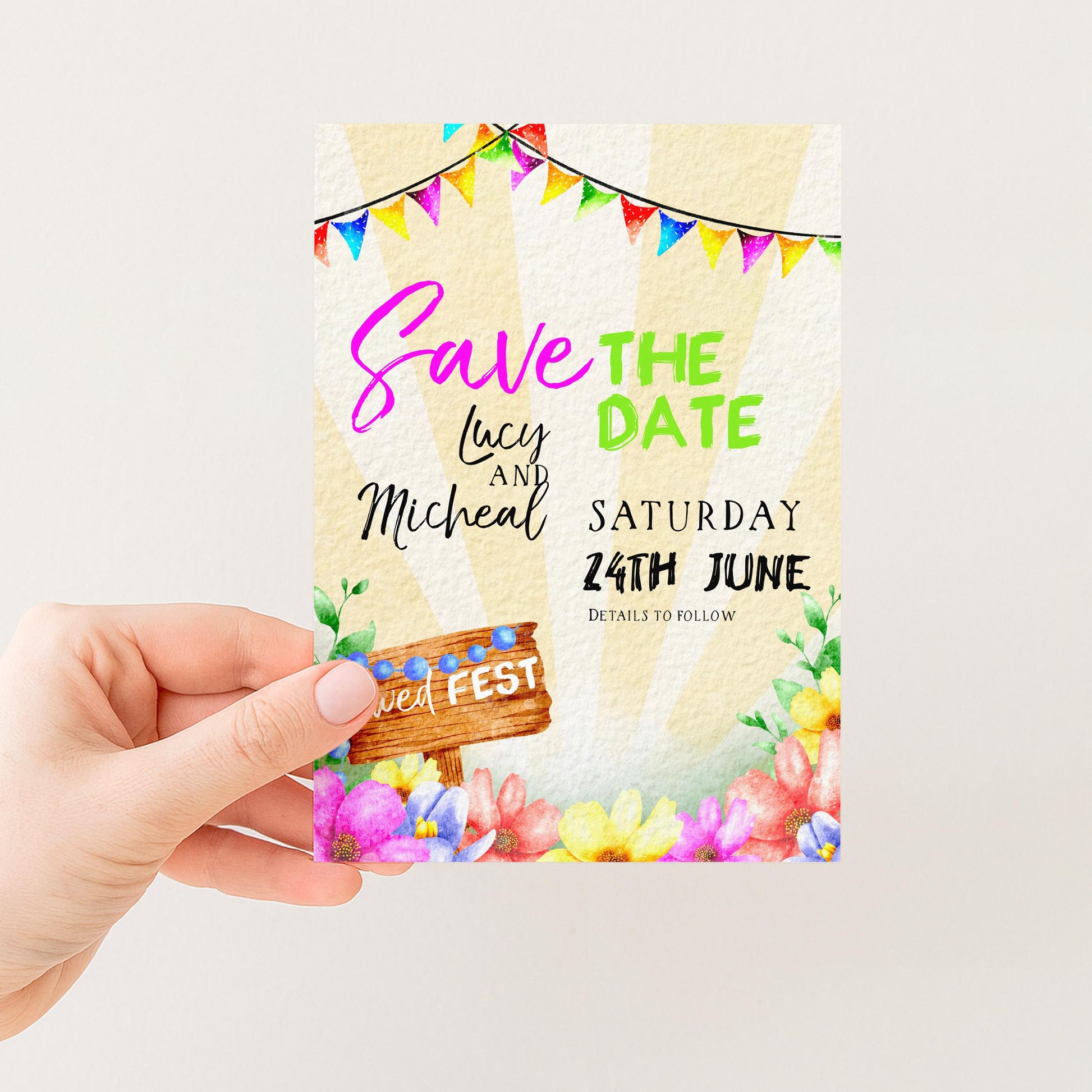 A hand holding a colorful wedding invitation card with text and decorative elements.