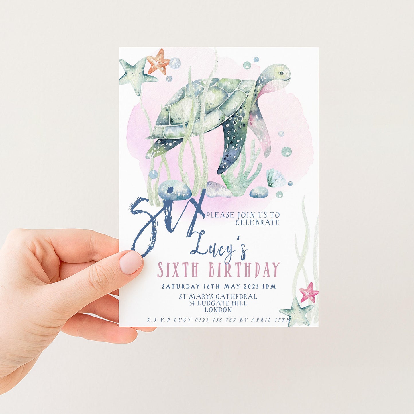 A hand holding a birthday invitation card with a turtle and starfish design, along with text inviting guests to a birthday celebration.