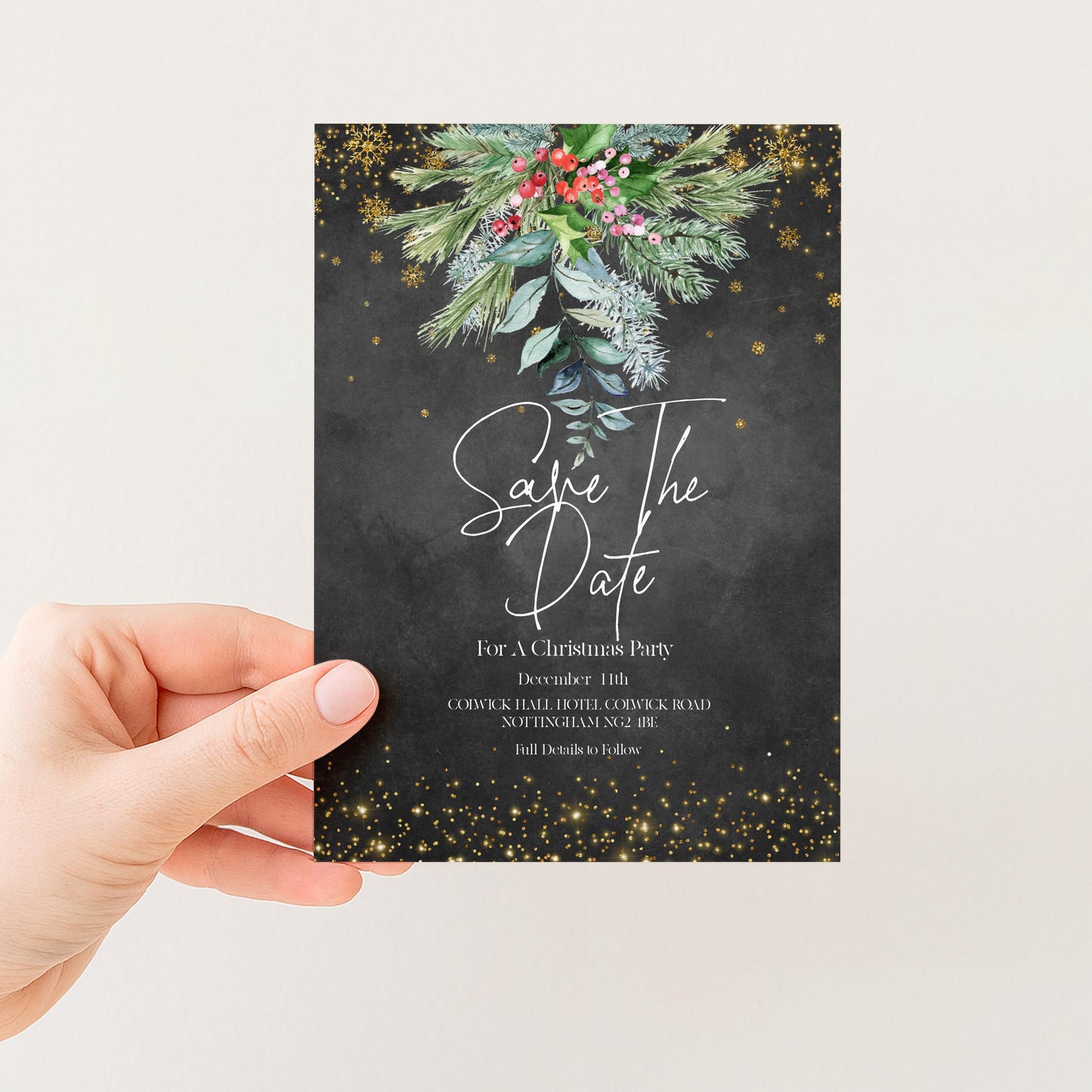A person is holding a card with a black background and a floral design, along with gold glitter and snowflakes. The card appears to be a save the date card for a Christmas party.