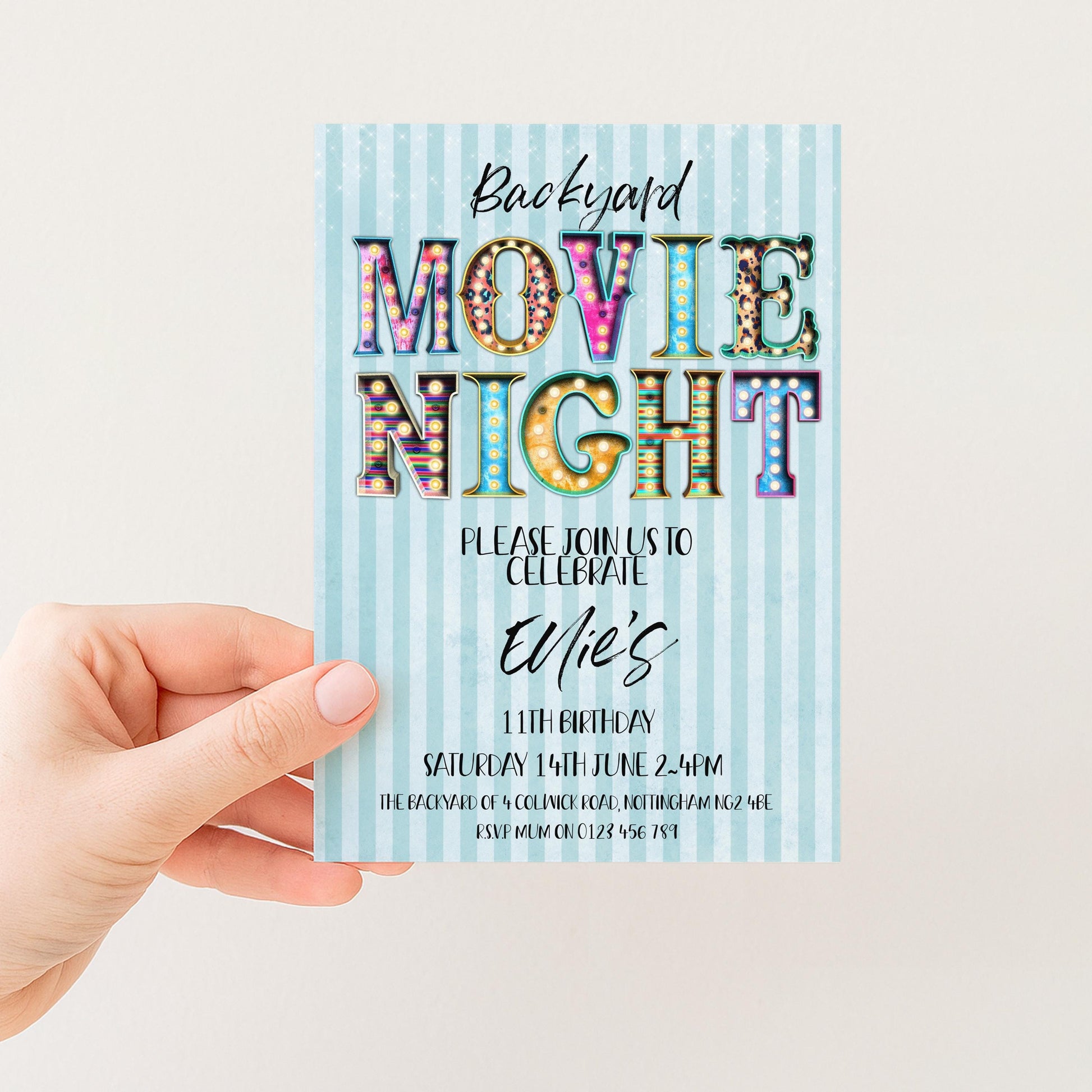 A hand holding a colorful invitation card for a backyard movie night event.