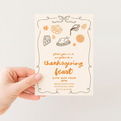 A person's hand holding a Thanksgiving feast invitation card with various Thanksgiving-themed illustrations and text.