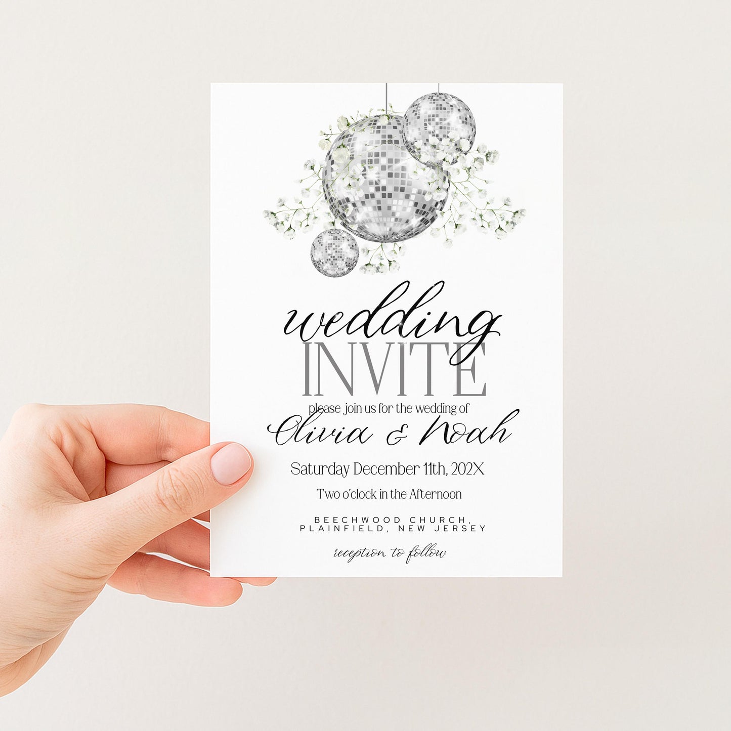A hand holding a wedding invitation card with a disco ball design and text.