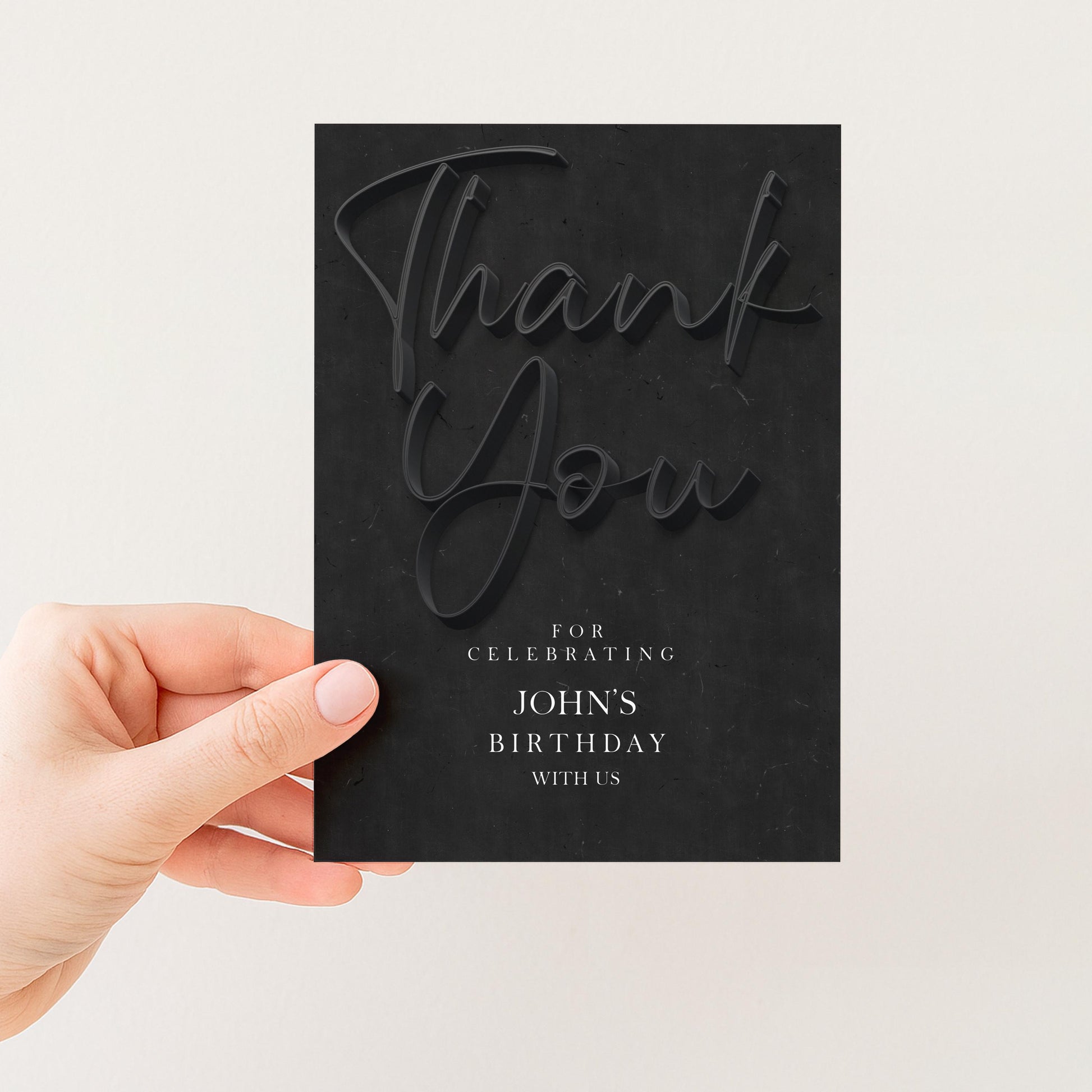 A hand holding a black card with the text "Thank You" on it.