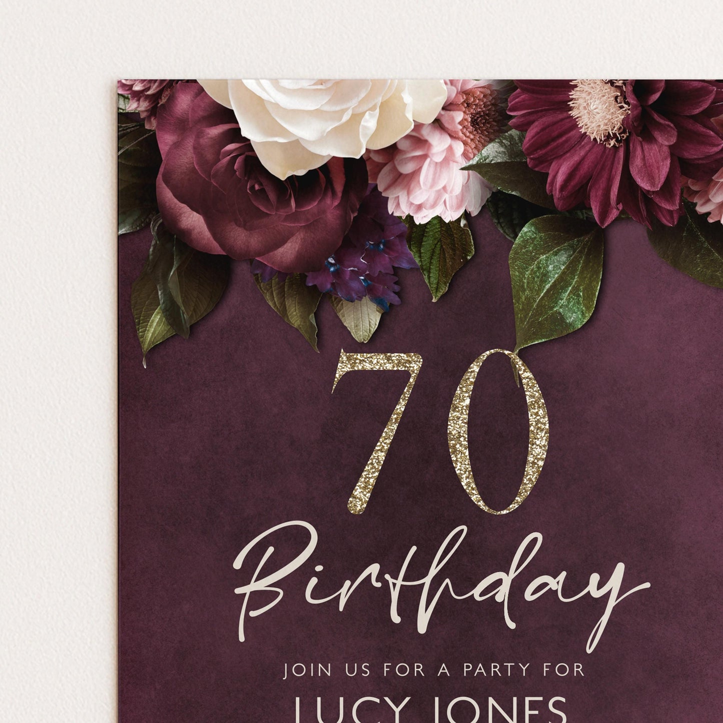 The image is a birthday invitation for a 70th celebration, featuring a floral design with white and burgundy flowers, along with the number 70 and the text "Join us for a party for LUCY JONES".