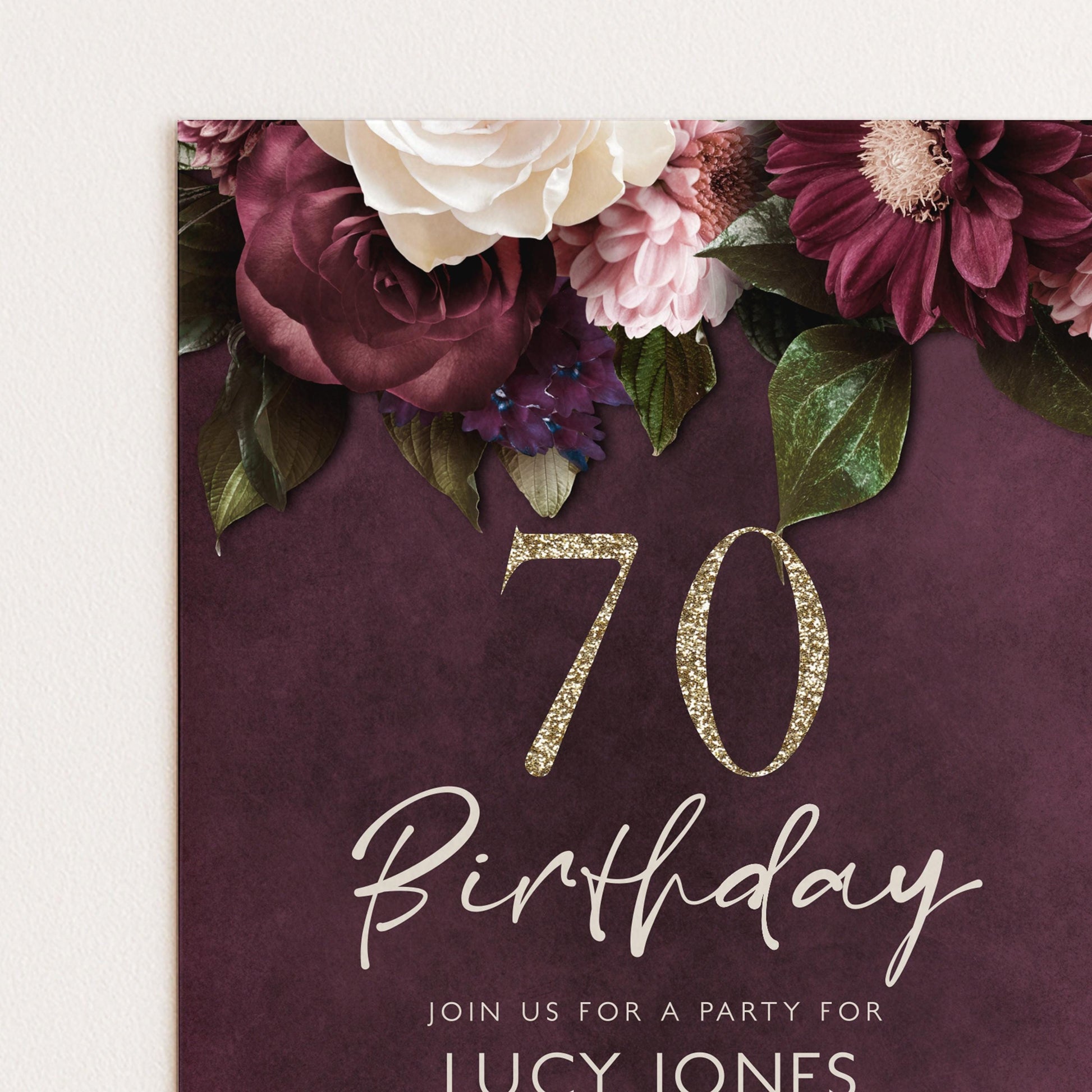 The image is a birthday invitation for a 70th celebration, featuring a floral design with white and burgundy flowers, along with the number 70 and the text "Join us for a party for LUCY JONES".