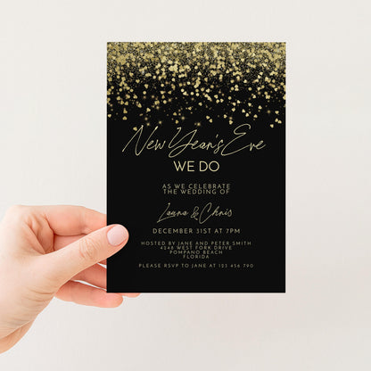 a hand holding a black invitation card with gold glitter and text.