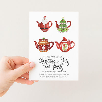 A hand holding a card with illustrations of Christmas-themed teapots and a message inviting people to a Christmas tea party.