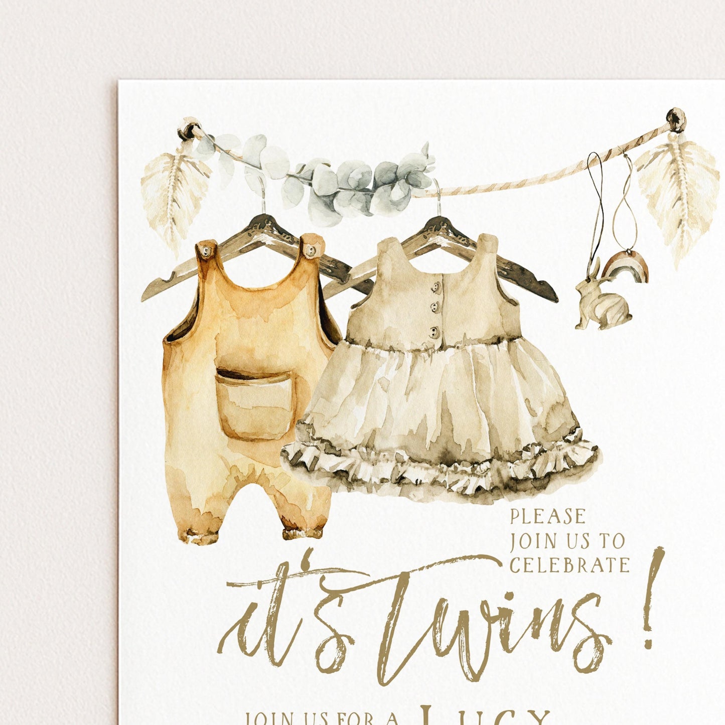 The image is a watercolor painting of two baby outfits hanging on a clothesline, with a sign below inviting people to "Join us for a Lucy's Twins" event.
